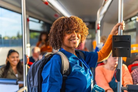 African american woman healthcare worker in blue scrubs carrying a backpack and smiling while