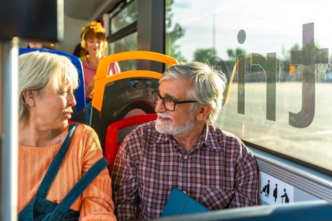Senior couple chatting and smiling as they travel together on a city bus, enjoying companionship