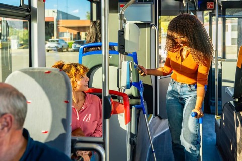 Young woman with crutches using contactless payment with smartphone to buy a ticket on public
