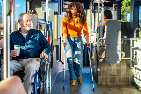 Commuters with disabilities, including a man in a wheelchair and a woman walking with crutches,