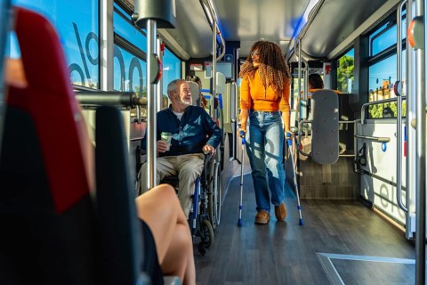 Senior man in a wheelchair and a woman using crutches traveling together on a modern, accessible