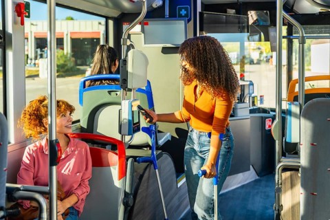 Woman with crutches paying for public transportation using smartphone at the ticket validator,