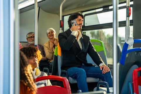 Man holding a vintage camcorder to his ear, pretending it is a cell phone, engaging in a playful