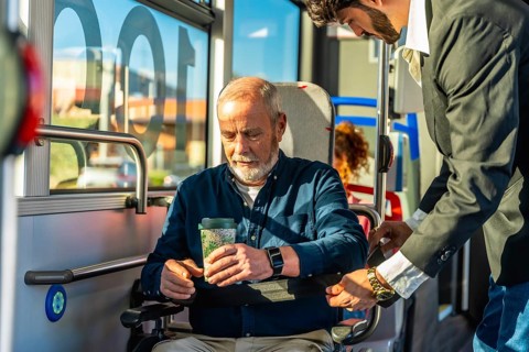 Young man assisting a senior passenger, ensuring safety and comfort while securing his wheelchair