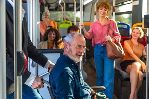 Man in a wheelchair being assisted on a public transit bus, representing accessibility and