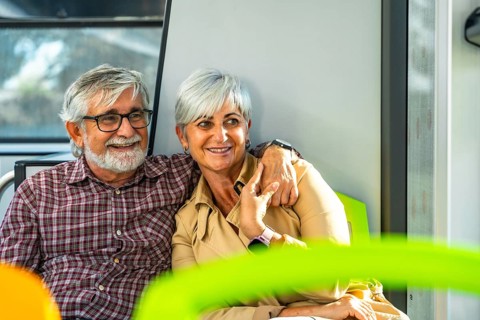 Senior couple embraces on a city bus, smiling and enjoying retirement travel together, warm