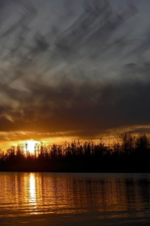Dramatic sunset with dark sky and golden reflections, Peenetal nature park Park,