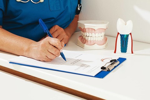 A dentist in a blue uniform studies patient information and prepares for treatment in a modern