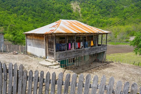 Old wooden house with veranda and colorful laundry, rural area, Imereti region, Imereti, Georgia