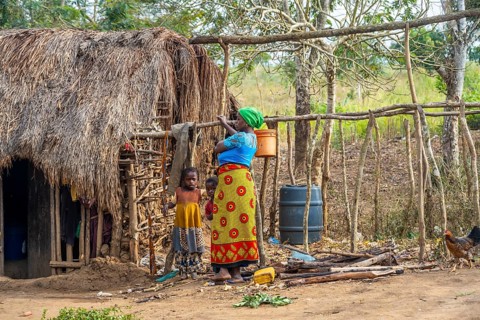 Mother and child in front of a simple traditional clay hut in a Sadaani village, Tanga, Tanzania