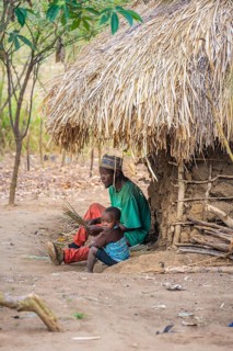 Father and child in front of a simple traditional clay hut in a Sadaani village, Tanga, Tanzania