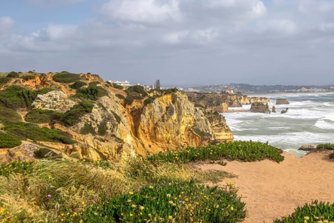 Cliff landscape on a seashore with cloudy sky and rough sea, Algarve, Portugal