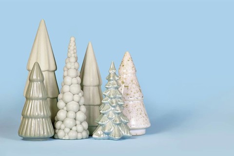Ornamental light green ceramic Christmas trees on blue background with copy space