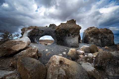 Eroded rock formations with rock tunnels, volcanic landscape with dramatic cloudy skies, Ciudad