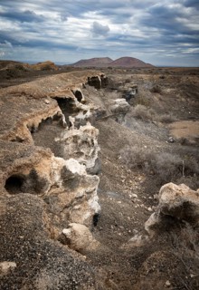 Eroded rock formations in volcanic landscape with dramatic cloudy skies, Ciudad Estratificada or