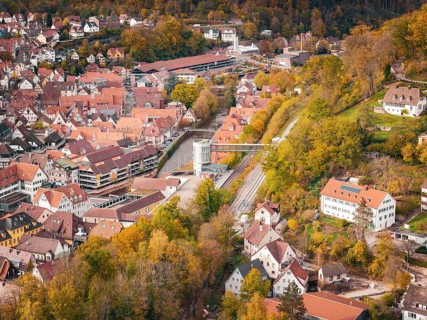 Wide angle view of the city with densely packed roofs and autumn trees in the area, Calw, Black