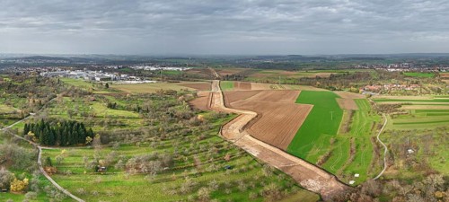 Panoramic picture of an extensive rural landscape under a grey sky, construction site, the South