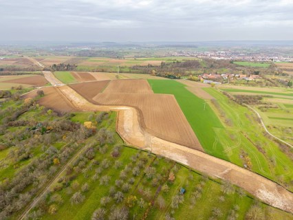 Aerial view of a rural region with fields and a faraway town, construction site, the South German