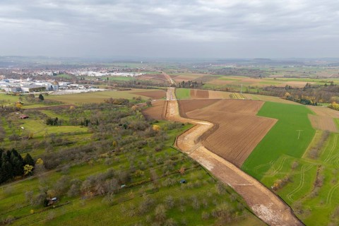 Aerial view of a rural area with fields and a city in the background under cloudy sky, construction