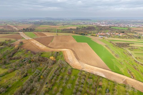 Extensive rural landscape with fields and power lines under a cloudy sky, construction site, the
