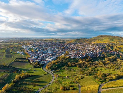 Aerial view of a village surrounded by hills and vineyards under cloudy sky, autumn,