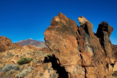 Rough rock formations under clear sky with a volcano in the distance, UNESCO World Heritage Site,