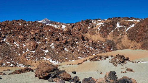 Barren volcanic landscape with rocks and snow trails under clear sky, UNESCO World Heritage Site,