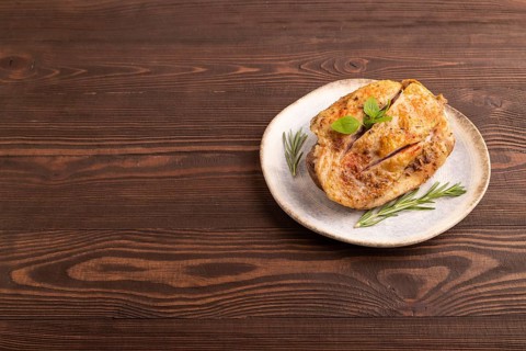 Fried Turkey Thigh with spices and rosemary on plate on brown wooden background. side view, copy
