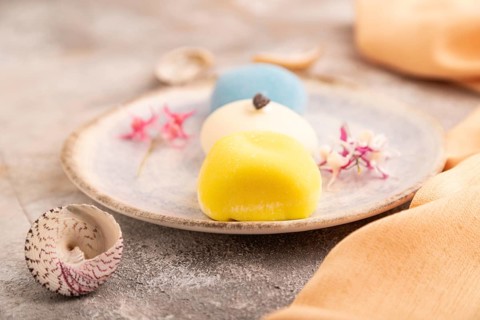 Japanese Mochi Cakes on brown concrete background and orange textile, side view, close up,