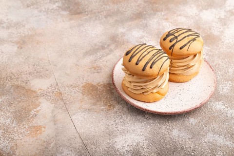 Caramel Cream Cakes on brown concrete background, side view, copy space