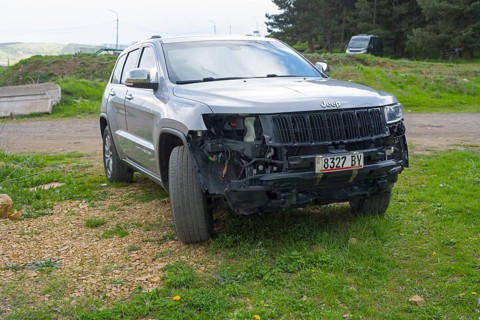 Damaged dark jeep standing on a roadside meadow, Georgia