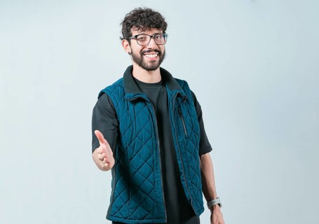 Friendly handsome guy greets you with open hand isolated. Male person extending her hand to the