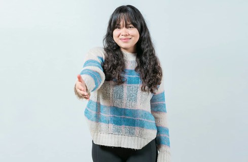 Attractive Asian girl greets you with open hand isolated. Cheerful woman extending her hand to the