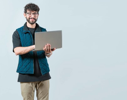 Smiling Bearded guy using laptop and looking at camera isolated. Handsome young man with glasses
