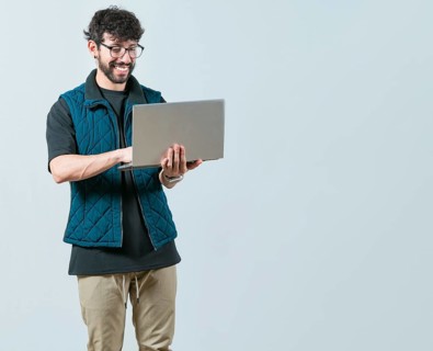 Portrait of Bearded guy using and looking laptop isolated. Handsome young man with glasses holding