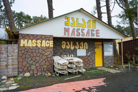 Colourful building with massage signs and stacked loungers outside, beach massage equipment with