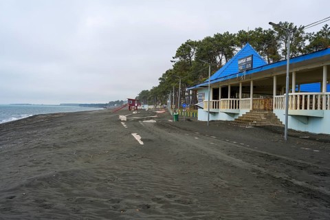 Promenade with buildings and trees along a cloudy beach, beach with magnetic sand, magnetite,