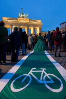 Athena Macke (costume designer) wears a dress with a long train in the shape of a bike path (bike