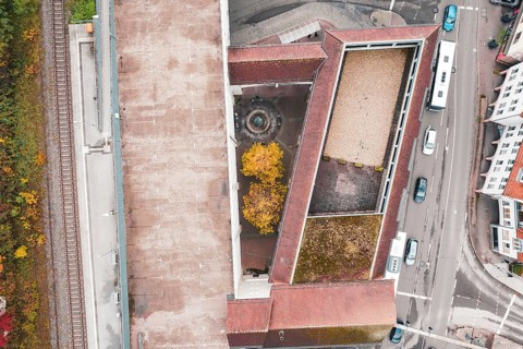 Urban aerial view with surrounding streets and buildings, a courtyard with a fountain and yellow