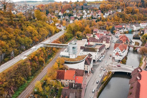 Idyllic small town in autumn colors with a river and bridge, surrounded by colorful trees. Railway