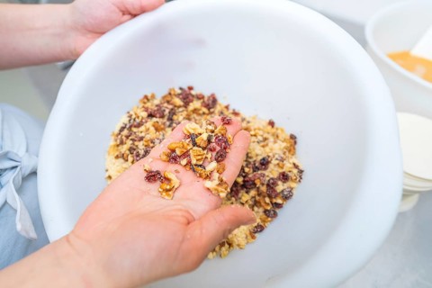Hands holding a mix of nuts and dried fruit in a white bowl, Christmas baking, Haselstaller Hof,