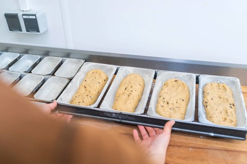 Baker prepares dough in metal box molds on a wooden board in a kitchen, Christmas baking,