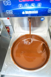 Liquid chocolate is poured into a large container in a machine, Weihnachtsbacken, Haselstaller Hof,