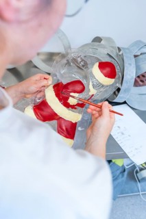 Person paints a plastic mold with red and white as part of a Christmas decoration, Christmas