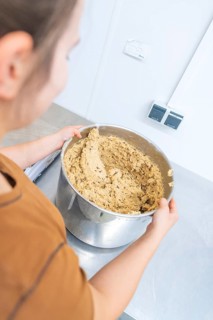 A person holds a large mixing bowl with dough in a kitchen, Christmas baking, Haselstaller Hof,