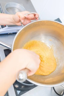 A person is stirring a yellow dough in a pan on a stove, Christmas baking, Haselstaller Hof,