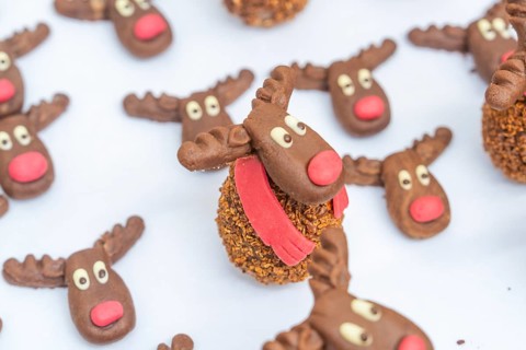 Reindeer chocolate chip cookies with red noses and white eyes, presented on a white background,