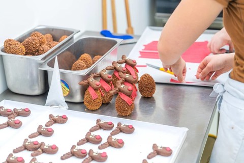 Chocolate brown reindeer cookies with red scarves are prepared in a bakery, Christmas baking,