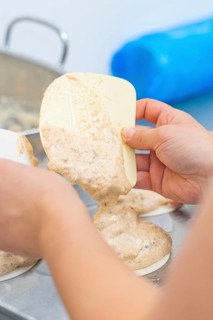 Dough is held by one hand with a silicone spatula and poured into a mold, Weihnachtsbacken,