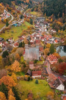A medieval village surrounds a castle, all bathed in rich autumn colors, Berneck Castle,